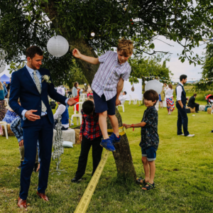 Rob in his wedding suit, standing next to a boy on a slackline, ready to help him if he falls