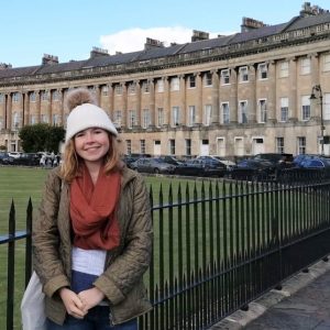 Abby wearing winter clothes and standing in front of a Regency terrace in Bath