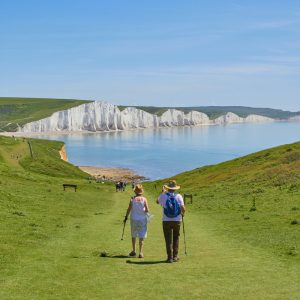 An elderly couple walking over the cliffs towards a bay and the sea
