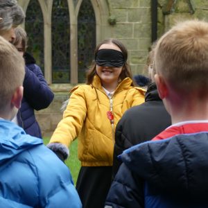 Girl in smiling with a blindfold on outside church learning what life is like as a bat