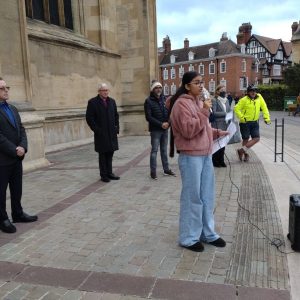 Gloucester teen Haroop speaks to the crowd from the steps of the Cathedral, with other community representatives standing behind
