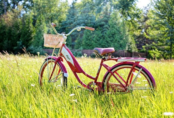 Red bicycle in a field with a basket on the front