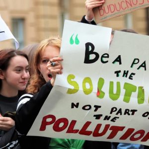 female teenager holding a banner saying 'Be a part of the solution not part of the pollution'