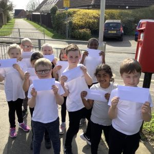 A group of children holding letters next to the letter box