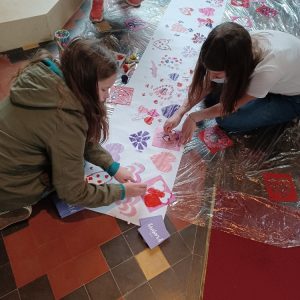 Three children working on a large piece of floor art