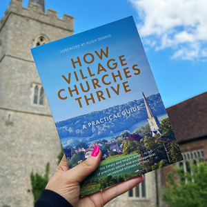 The book How Village Churches Thrive being held up with a church in the background