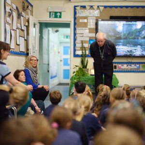 The Archbishop leans forward to listen to a child